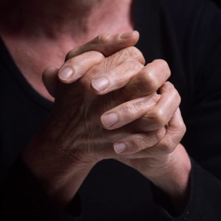 Fingers intertwined convey a sense of contemplation and tranquility. The soft lighting highlights