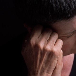A woman with short hair rests her head on her hand, conveying deep contemplation and introspection