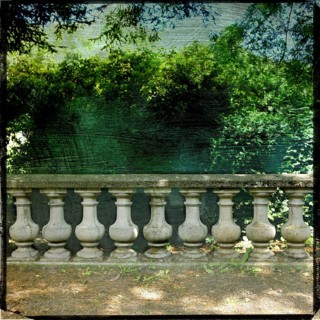 A garden balustrade exhibits a rich textured effect, framed by lush greenery and a captivating view
