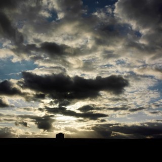 A stunning display of clouds fills the sky above rural as the sun sets, casting shadows over the