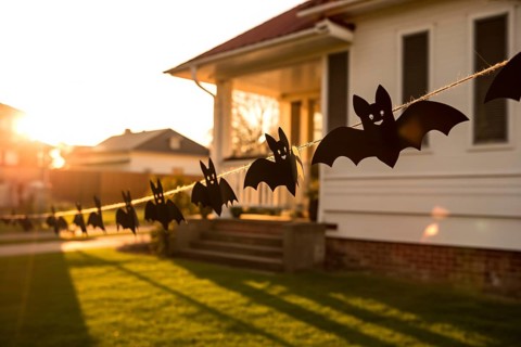 Halloween garland with black paper bats hanging on house facade. Festive outdoor decoration for