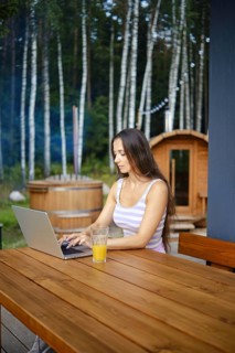 A woman finishes remote work while sitting on the terrace in the evening and is about to go to