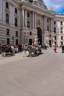 Everyday scene full of tourists and horse-drawn carriages on Michaelerplatz in front of the