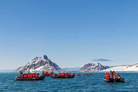 Group of Zodiacs in front of mountains with snow, sea, Fugelfjorden, Spitsbergen, Svalbard