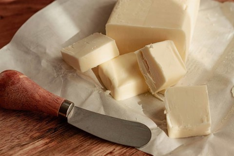 Butter briquette, on wrapping paper, wooden chopping board and butter knife, breakfast, rustic