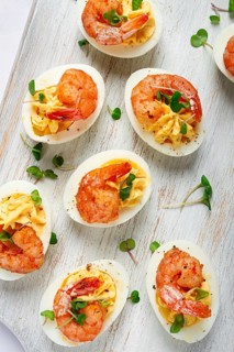 Boiled eggs stuffed with yolk and seasoned with mayonnaise, stuffed eggs with shrimp, on a white