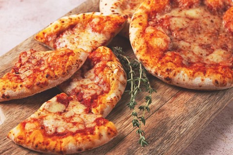 Four pizzetta Margaritas, on a cutting board, on a light gray surface, top view