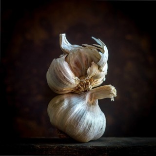 Garlic cloves are arranged carefully against a black background, emphasizing their natural texture