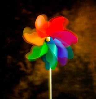 A bright pinwheel spins playfully, showcasing vibrant colors of red, blue, green, and orange. This