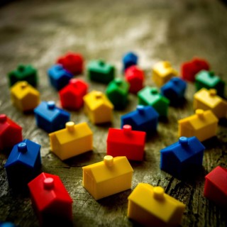 Numerous small houses in bright colors are arranged on a textured wooden surface, inspiring a