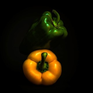 Two vibrant bell peppers, one green and one yellow, are prominently displayed against a black