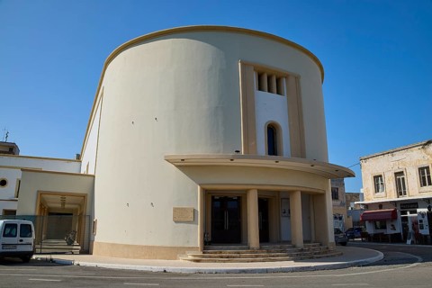 Cinema, A modern, round building with columns, cream-coloured façade under a clear blue sky,