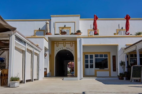 White building with entrance and decorative umbrellas on a terrace on a sunny day, Armando