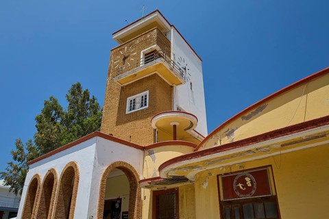 Market Hall, Agora, Historic Clock Tower with arches and surrounding trees under bright sunshine,