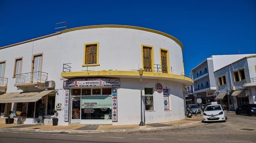 White corner building with shops and parked cars on the street, Armando Bernabiti, Historicism,