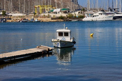 Small boat at the pier in a picturesque harbour with sailing yachts in the background, Lakki,