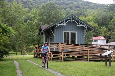 Clover Lick, West Virginia - A bicyclist rides past a restored train station on the Greenbrier