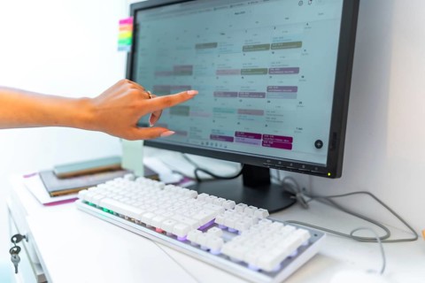 Beautician managing appointments, consulting online schedule on computer in a beauty salon,