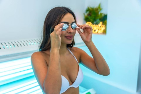 Client putting on protective eyewear preparing for tanning session in a solarium at a beauty center
