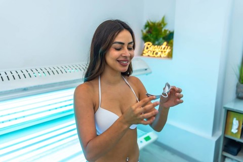 Client preparing for a uv tanning session, adjusting protective eyewear while getting ready in a