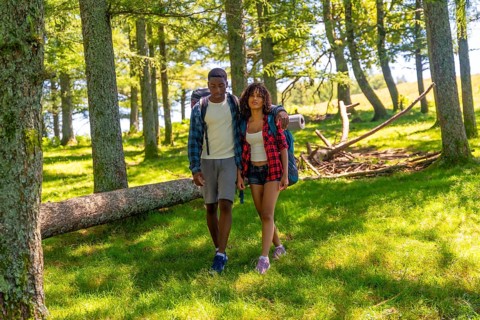 Young couple hiking through a lush forest, enjoying a summer trekking adventure filled with