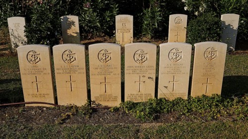 Rows of evenly spaced gravestones in the sunlight, surrounded by green vegetation, sinking of the H