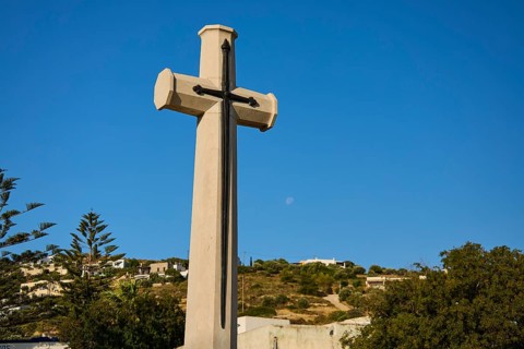 Large cross in front of blue sky with moon, landscape in the background, military cemetery,