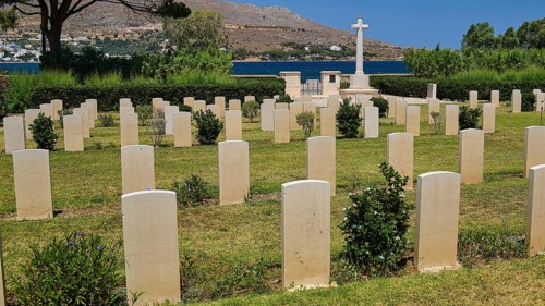 Cemetery with many gravestones in front of mountains and sea under blue sky, Military Cemetery,