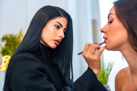 Makeup artist carefully applying lip liner on a client, enhancing her natural beauty in a