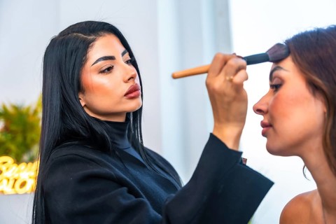 Makeup artist skillfully applying foundation on a client's face in a beauty salon, using a brush