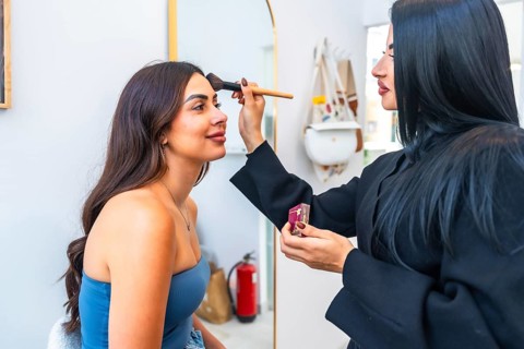 Professional makeup artist applying foundation on a client's face using a brush, enhancing her