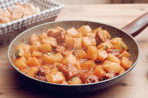 Hearty vegetable stew with meat, in a frying pan, with freshly baked bread, close-up