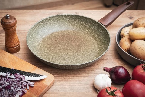 Fresh ingredients including potatoes, garlic, tomatoes, and onions are arranged on a wooden table