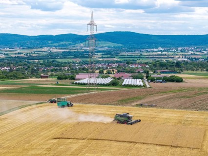 Harvesters and tractors in a field under a blue sky in a mountainous landscape, Korb im Rems