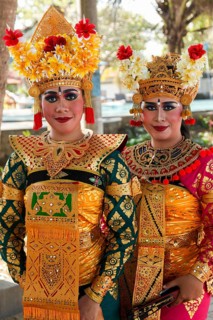 Legong dancers in traditional costumes, wearing makeup, in front of a dance performance in Sanuar,