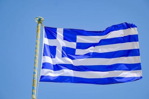 Ano Mera, Mykonos, Cyclades, Greece - Greek national flag fluttering on the flag pole on the roof