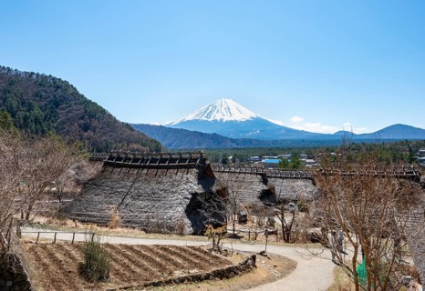 Iyashinosato open-air museum, old Japanese village with traditional houses, at the back volcano Mt.