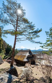 Iyashinosato open-air museum, old Japanese village with traditional houses, at the back volcano Mt.