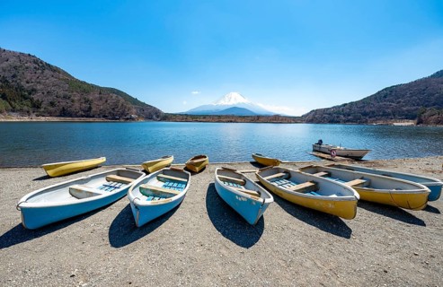 Rowing boats on shore, view across the lake to Mt Fuji volcano, Motosu Lake, Yamanashi Prefecture,