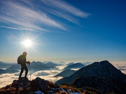 Mountaineer looking at blue-colored silhouette of mountains, fog in the valley, Hochstaufen,
