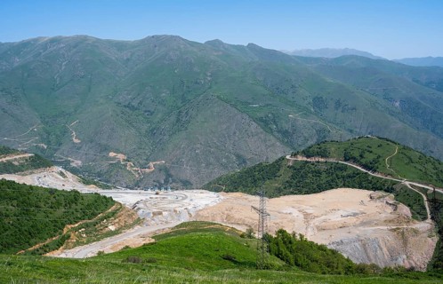Industrial landscape with mining pit surrounded by green mountains, view of a quarry near Qajaran,