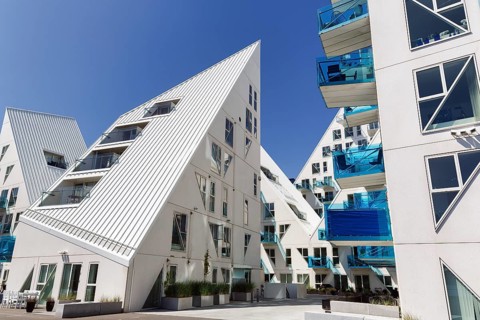 Distinctive white residential complex, turquoise balconies against blue sky, pyramid-shaped