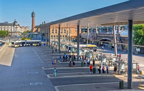 Commuters waiting for transit buses at bus stop of public transport company De Lijn at train