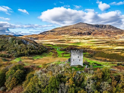 Autumn colours over Castell Dolwyddelan and Eryri Mountains from a drone, Snowdonia, Conwy County