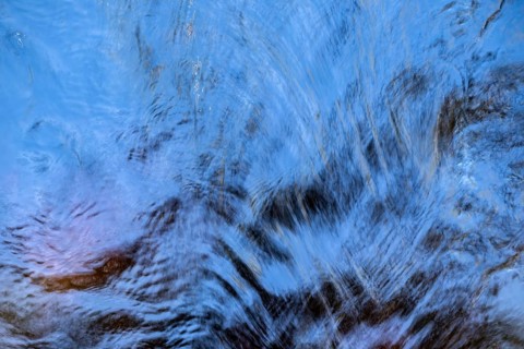 Shimmering blue water surface of a stream, current, light reflections, abstraction, long exposure,