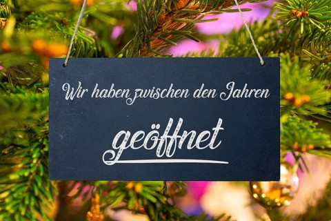 (photo montage) Christmas opening times: sign with the inscription WE ARE OPEN BETWEEN THE YEARS in