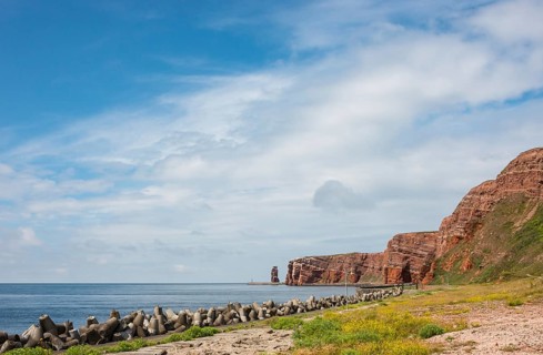 Wide, sunny coastline with concrete tetrapods by the sea, coastal protection, protective wall,
