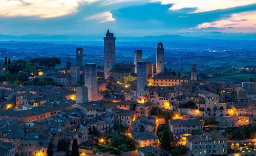 City view of San Gimignano at dusk, gender towers and medieval buildings, Tuscany, Italy
