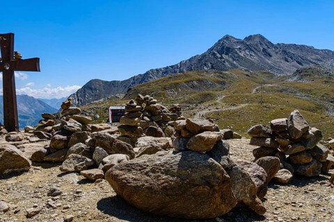 Stone men in front of an alpine landscape at the Timmelsjoch rest house on the border between