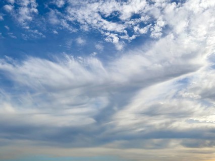 Above white medium-height clouds Altocumulus floccus below Altostratus in front of above blue sky,